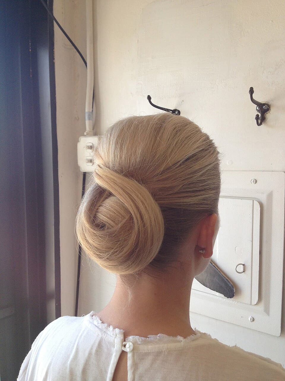 A detailed, high-resolution visual of the wrapped, horizontal knot positioned strictly at the nape, defining the parameters of the chignon.